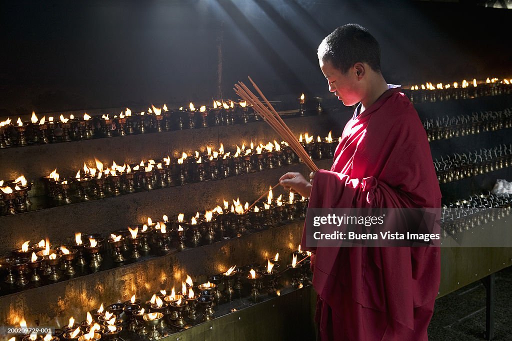 China, Tibet, Buddhist monk lighting insense at Jokhang monastery
