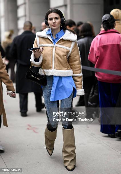 Guest is seen wearing a tan and white faux fur jacket, blue button down, blue jeans and tan boots outside the Eckhaus Latta show during NYFW F/W 2024...