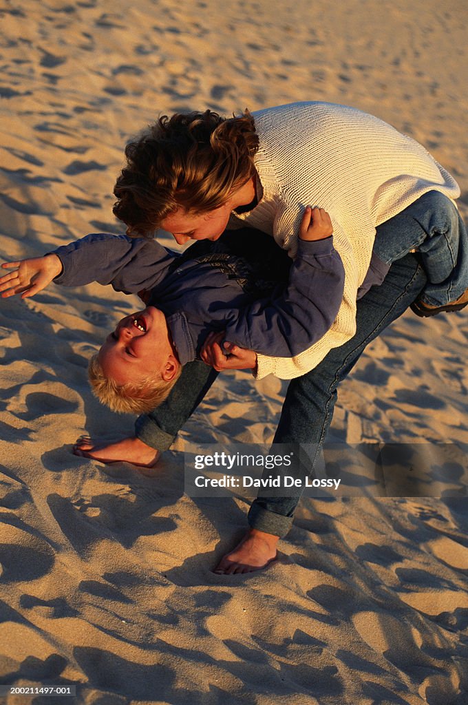 Woman holding boy upside down