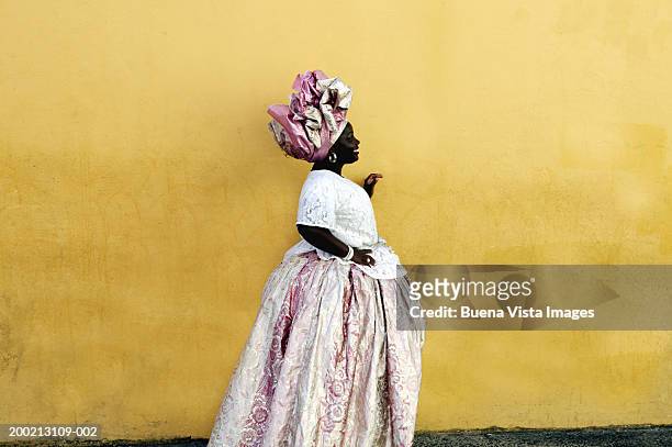 woman wearing traditional brazilian clothing, standing by yellow wall - brazilian culture foto e immagini stock