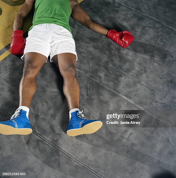 young male boxer lying on back on floor, overhead view - boksbroek stockfoto's en -beelden