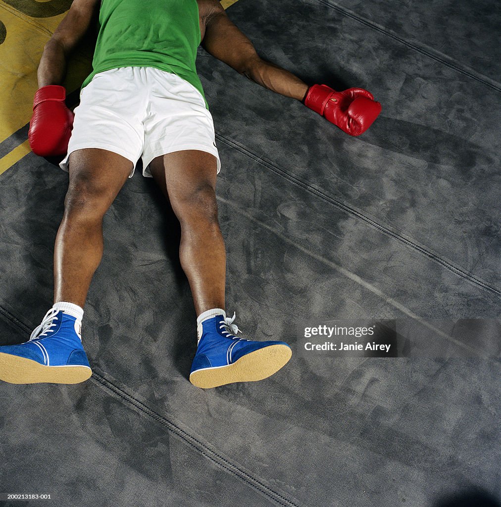 Young male boxer lying on back on floor, overhead view