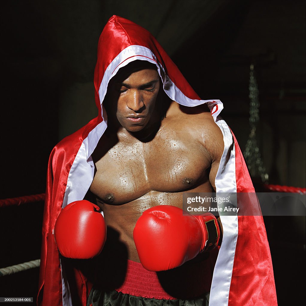 Young male boxer wearing hooded cape in ring
