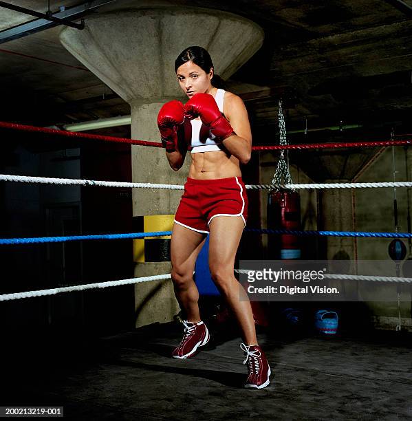 young female boxer in ring, gloves raised, portrait - womens boxing fotografías e imágenes de stock