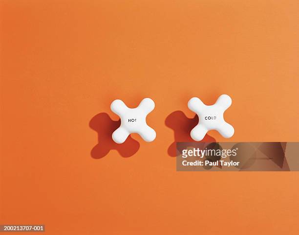 hot and cold tap handles on orange background - tap stockfoto's en -beelden