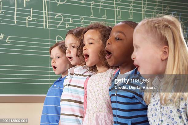 five school children (5-10) singing in class, close-up - enfant chant classe photos et images de collection