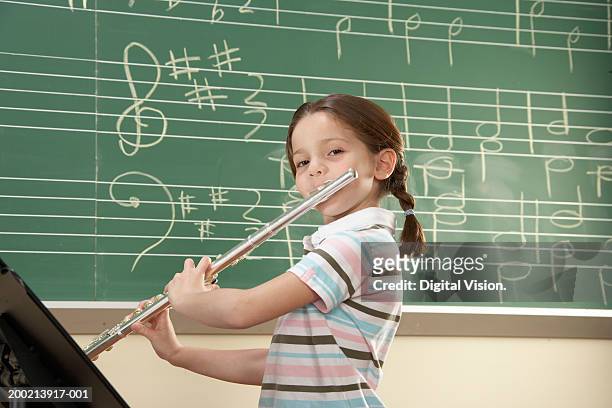 schoolgirl (5-10) playing flute, smiling, portrait - children music stockfoto's en -beelden