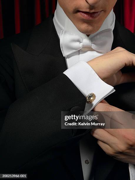 man wearing tuxedo, adjusting cufflink, mid section, close-up - gemelli da polso foto e immagini stock