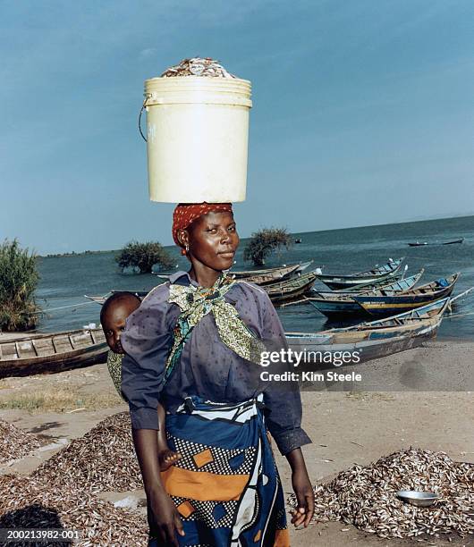 woman carrying child on back and bucket of fish on head, portrait - back of womens heads stock-fotos und bilder