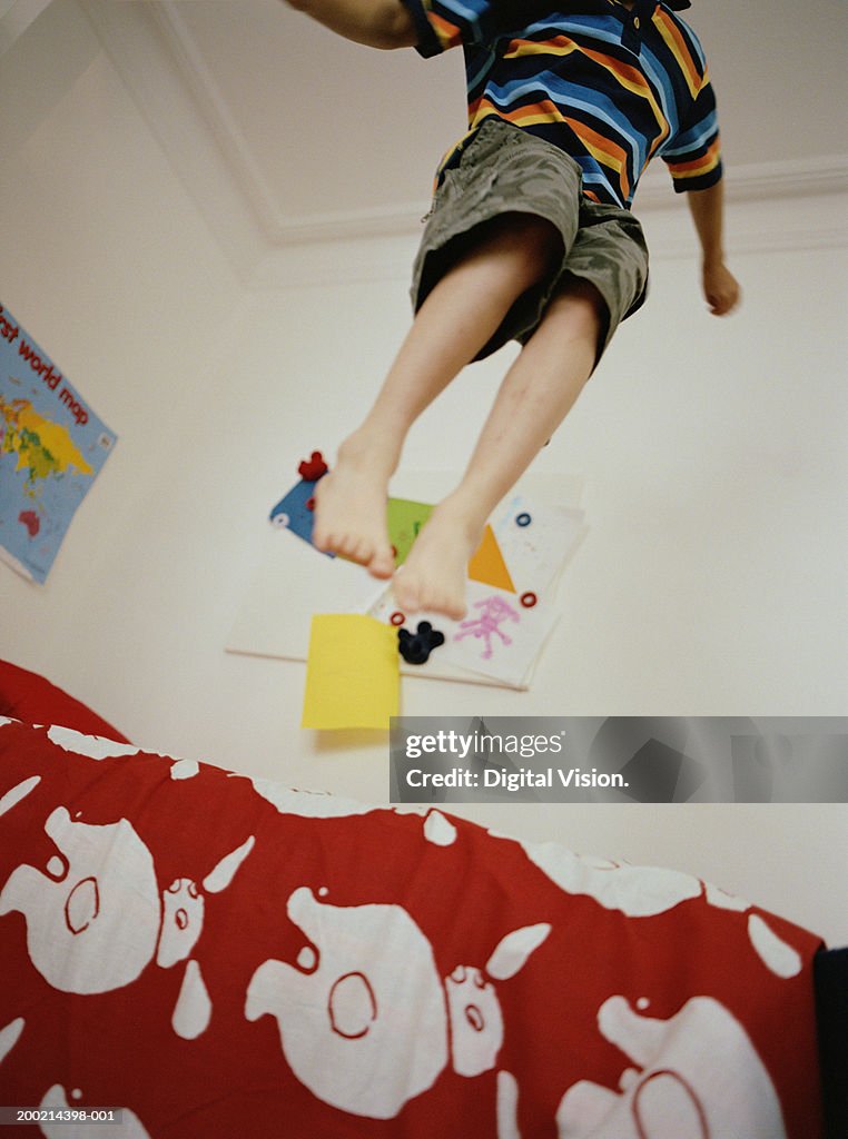 Boy (6-8) jumping on bed, low angle view