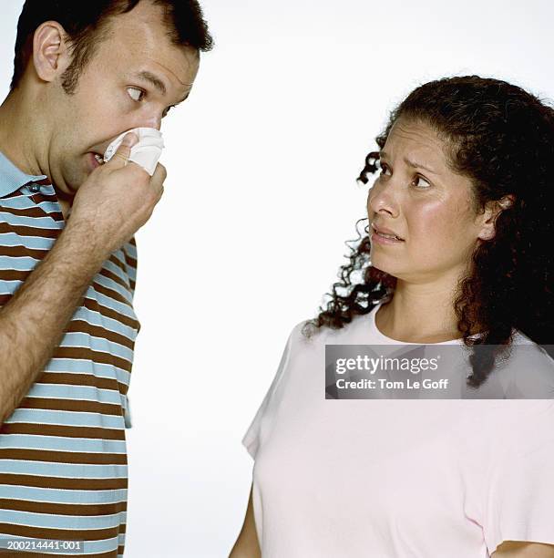 woman watching man blowing nose - closeup of a hispanic woman sneezing foto e immagini stock