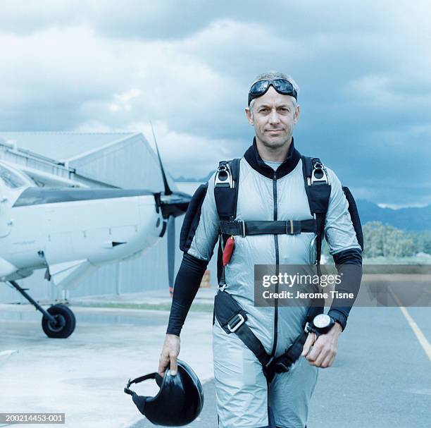 mature man wearing parachute harness by plane, portrait - flying goggles stock photos et images de collection