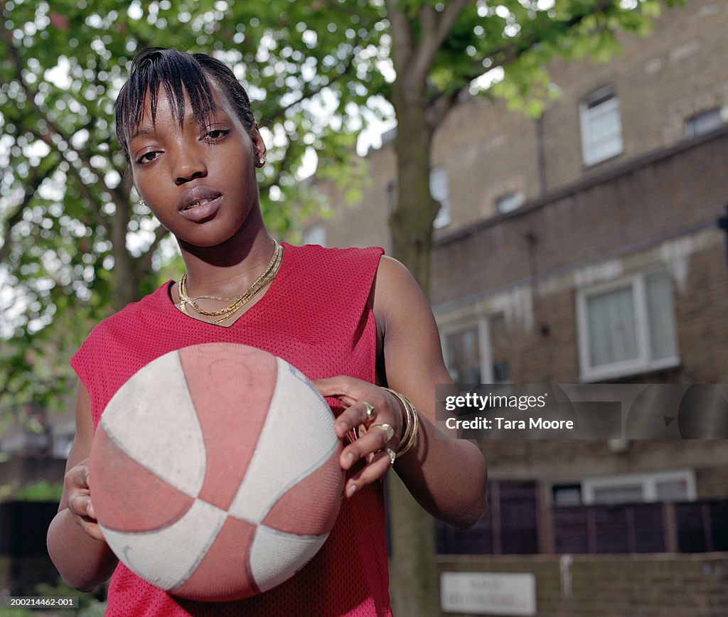 Young woman holding basketball, portrait, close-up