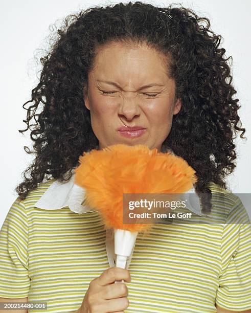 woman holding feather duster up to face, twitching nose, eyes closed - closeup of a hispanic woman sneezing foto e immagini stock