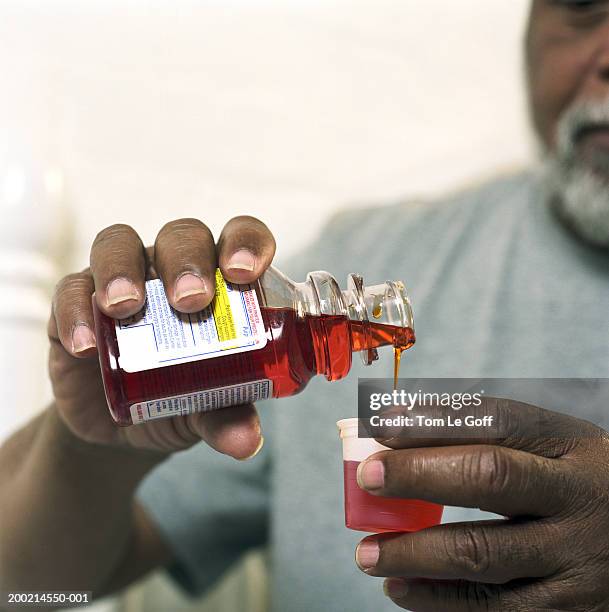 senior man pouring medicine out of bottle, close-up - hustenmittel stock-fotos und bilder