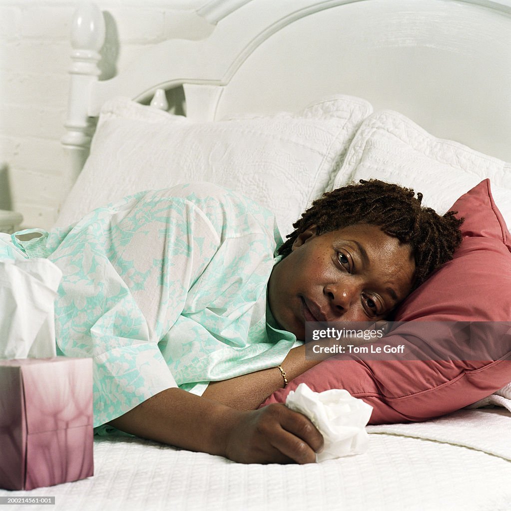 Woman lying in bed with box of tissues, portrait, close-up