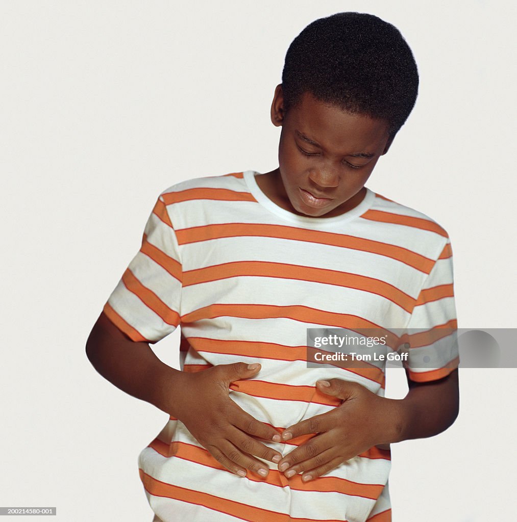 Boy (9-11) holding stomach, grimacing