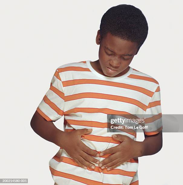 boy (9-11) holding stomach, grimacing - boy holding picture cut out stockfoto's en -beelden