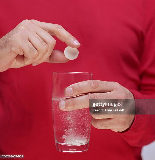 man dropping second tablet into fizzing glass of water, close-up - effervescent tablet stock pictures, royalty-free photos & images