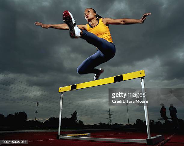 young sportswoman hurdling, low angle view - hurdling photos et images de collection