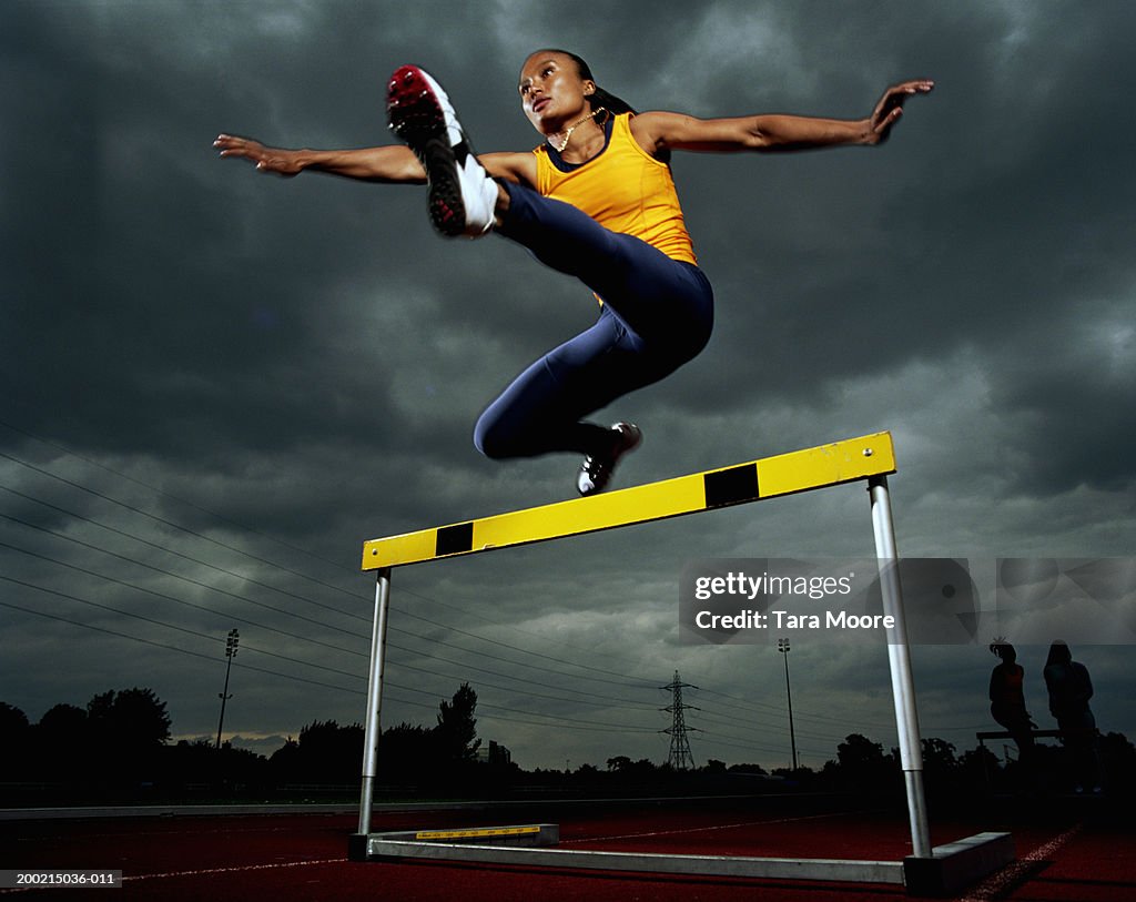 Young sportswoman hurdling, low angle view