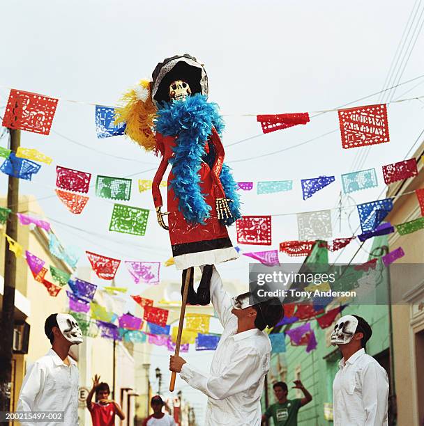 three men wearing skeleton masks looking up at day of the dead puppet - dag-van-de-doden stockfoto's en -beelden