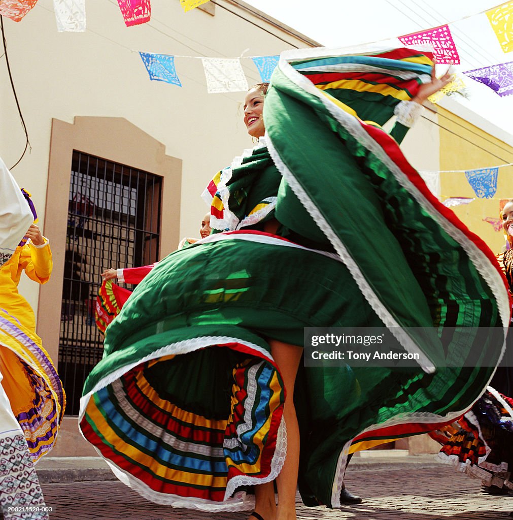 Young woman wearing traditional dress, dancing at fiesta