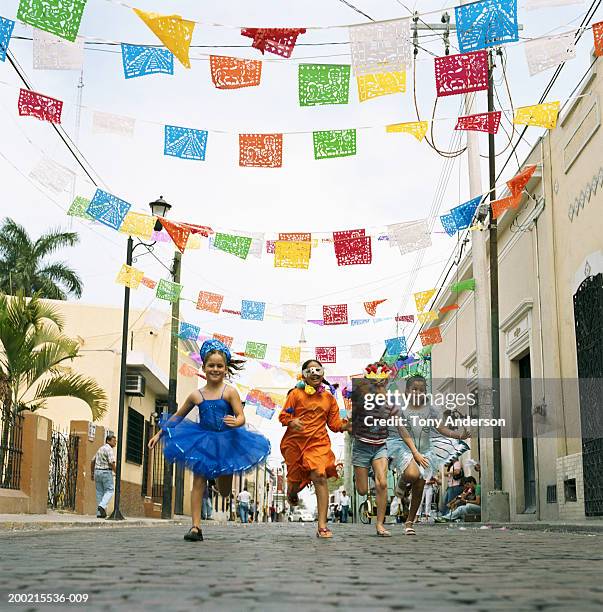 four girls (5-9) running in street at fiesta - tradicional fotografías e imágenes de stock