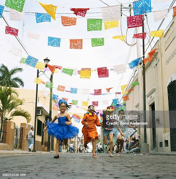 four girls (5-9) running in street at fiesta - carnaval feestelijk evenement stockfoto's en -beelden