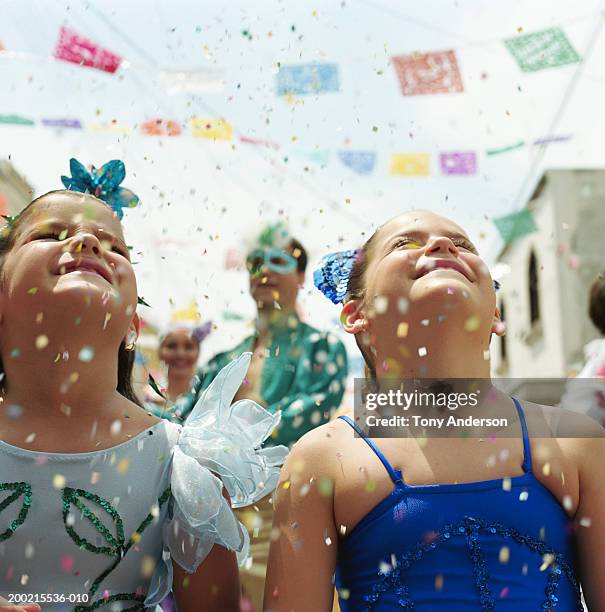 two girls (5-9) standing under falling confetti at fiesta - fiesta latina stock-fotos und bilder