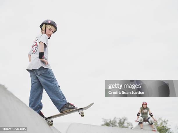 boy (10-12) on skateboard, girl in background - ten to fifteen stock pictures, royalty-free photos & images