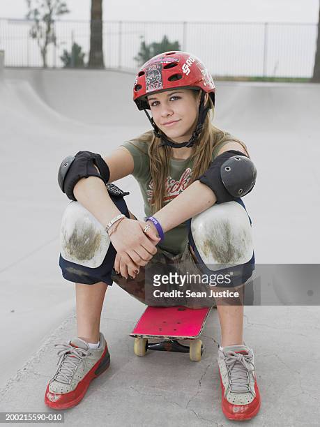 teenage girl (14-16) sitting on skateboard, portrait - kneepad stock pictures, royalty-free photos & images