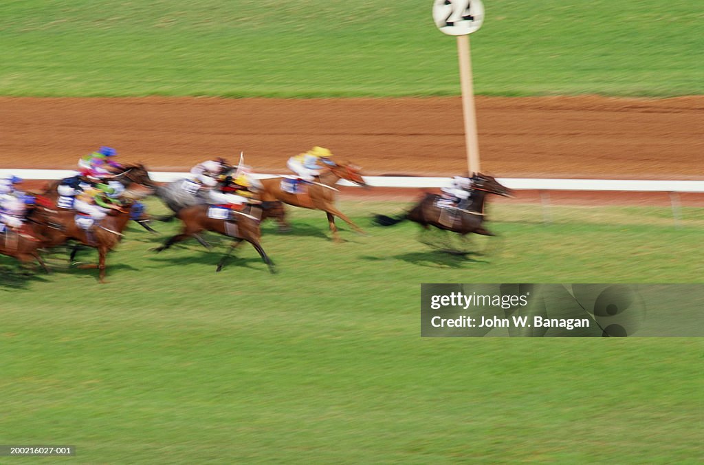 Jockeys racing horses on race track (blurred motion)