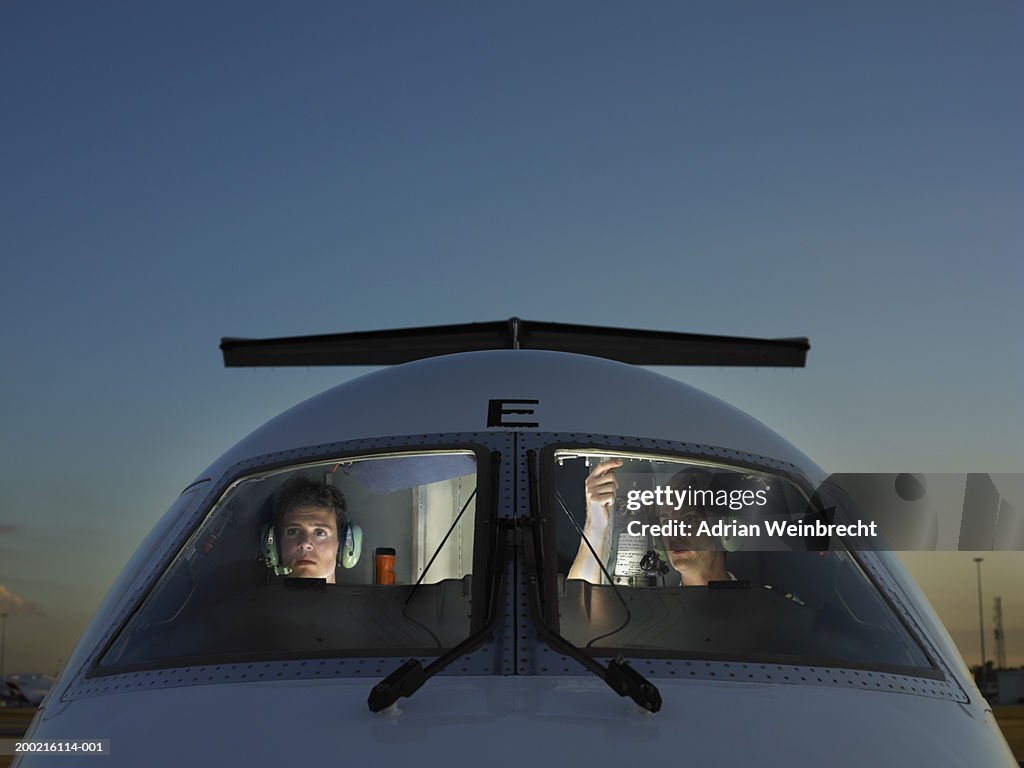 Two pilots in cockpit of plane, view through glass