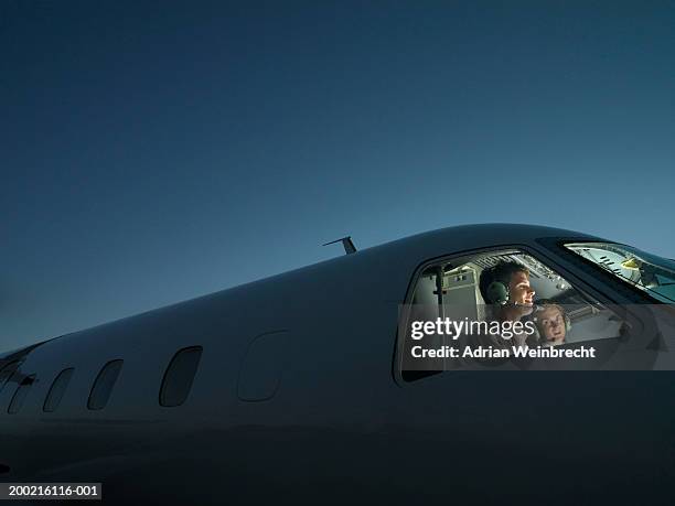 two pilots in illuminated cockpit of plane, smiling - piloting stock-fotos und bilder