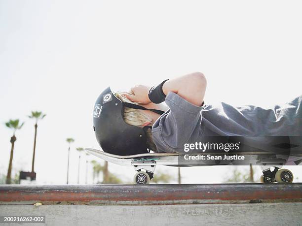 boy (10-12) laying on skateboard with hand on head - boy 10 11 stock pictures, royalty-free photos & images