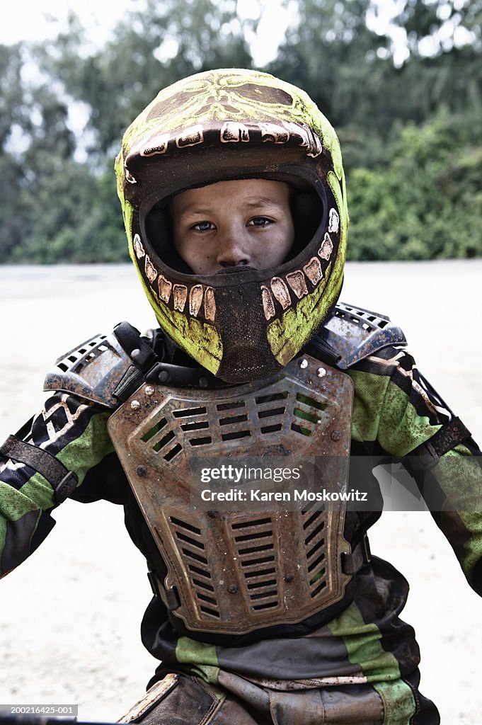 Boy (11-13) wearing protective gear, sitting on dirt bike, portrait
