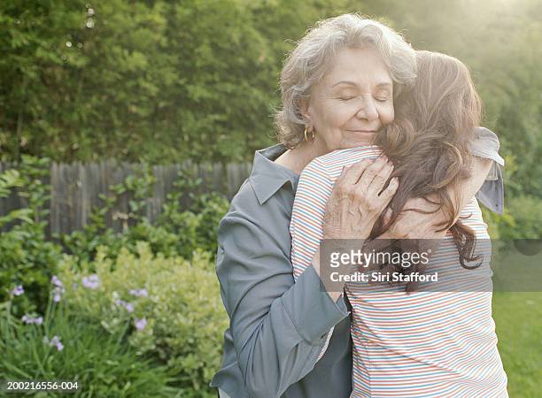 grandmother embracing adult granddaughter - omhelzen stockfoto's en -beelden