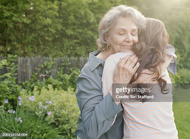 grandmother embracing adult granddaughter - cuddling stock pictures, royalty-free photos & images