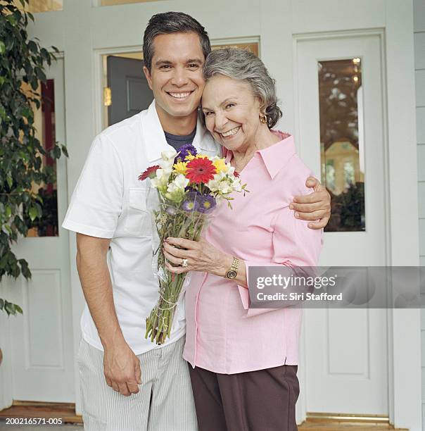 young man embracing grandmother in front of house - old woman young man stock pictures, royalty-free photos & images