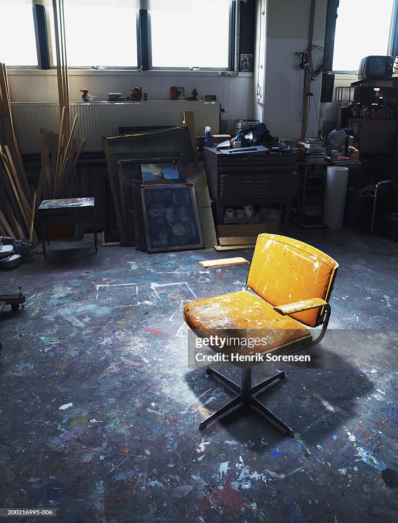 Empty chair in artists studio splattered in paint