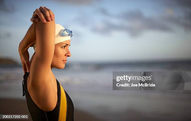 female triathlete doing stretching exercise on beach - triathlon swim stock pictures, royalty-free photos & images