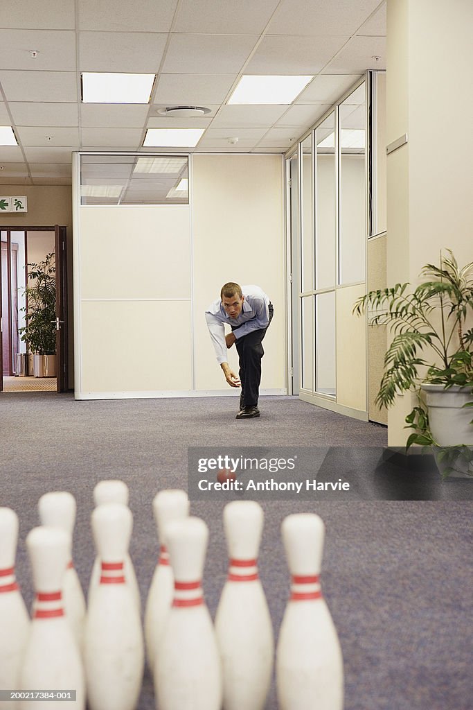 Man playing skittles in office corridor (Focus on man)