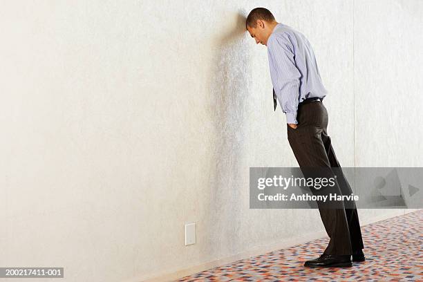 businessman leaning with forehead against wall - leaning stock pictures, royalty-free photos & images