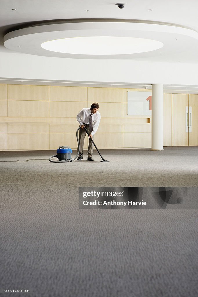 Man vacuuming in area of light under ceiling window
