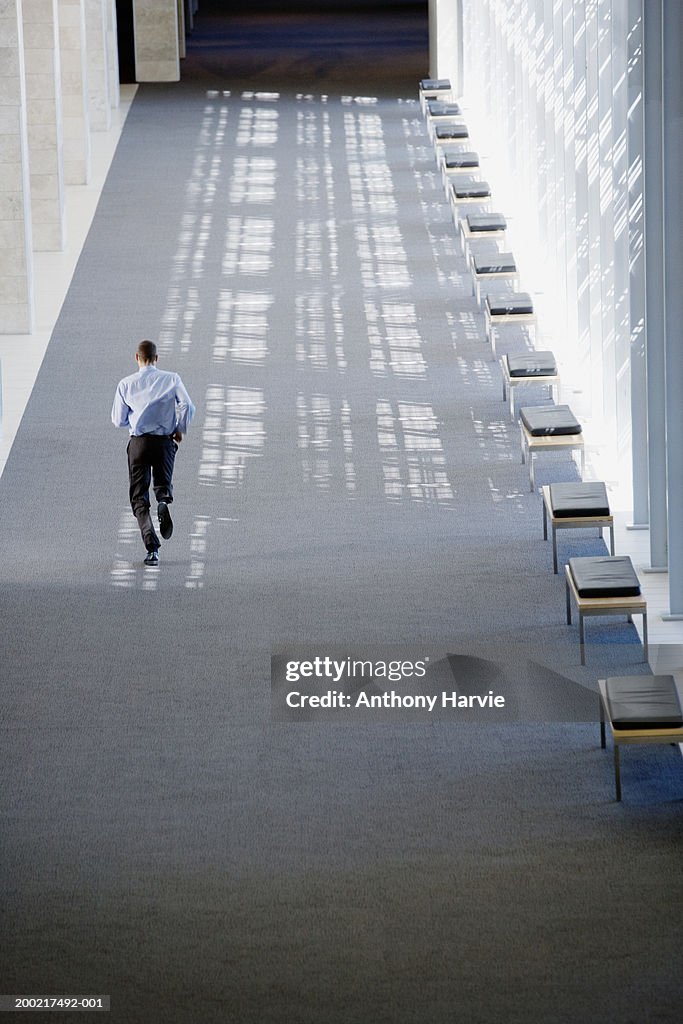 Man running down wide corridor, rear view