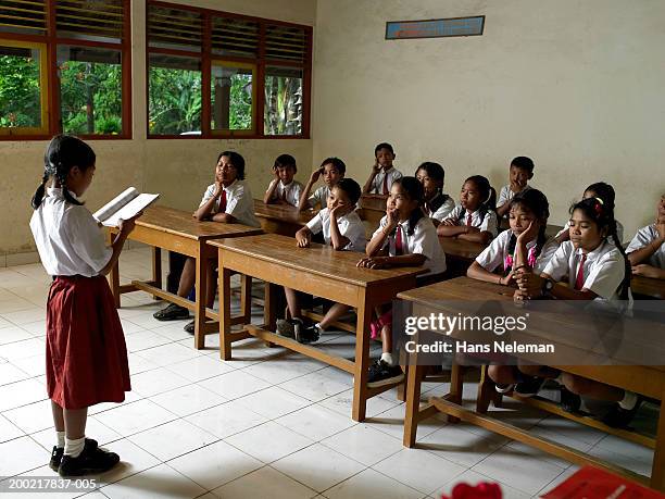 girl (8-10) reading in front of class, side view - etnia indonésia imagens e fotografias de stock
