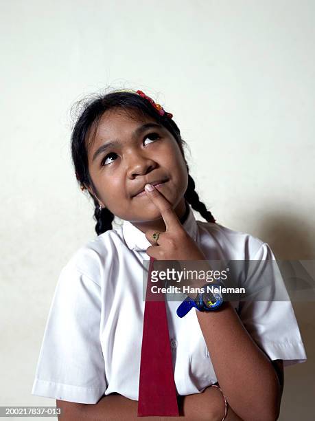 schoolgirl (10-12) with finger on mouth looking upward, close-up - school tie stock pictures, royalty-free photos & images