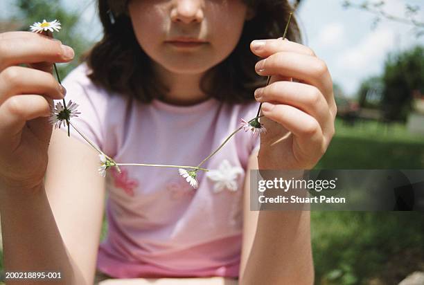girl (7-9) holding up daisy chain, close-up - ketting van madeliefjes stockfoto's en -beelden