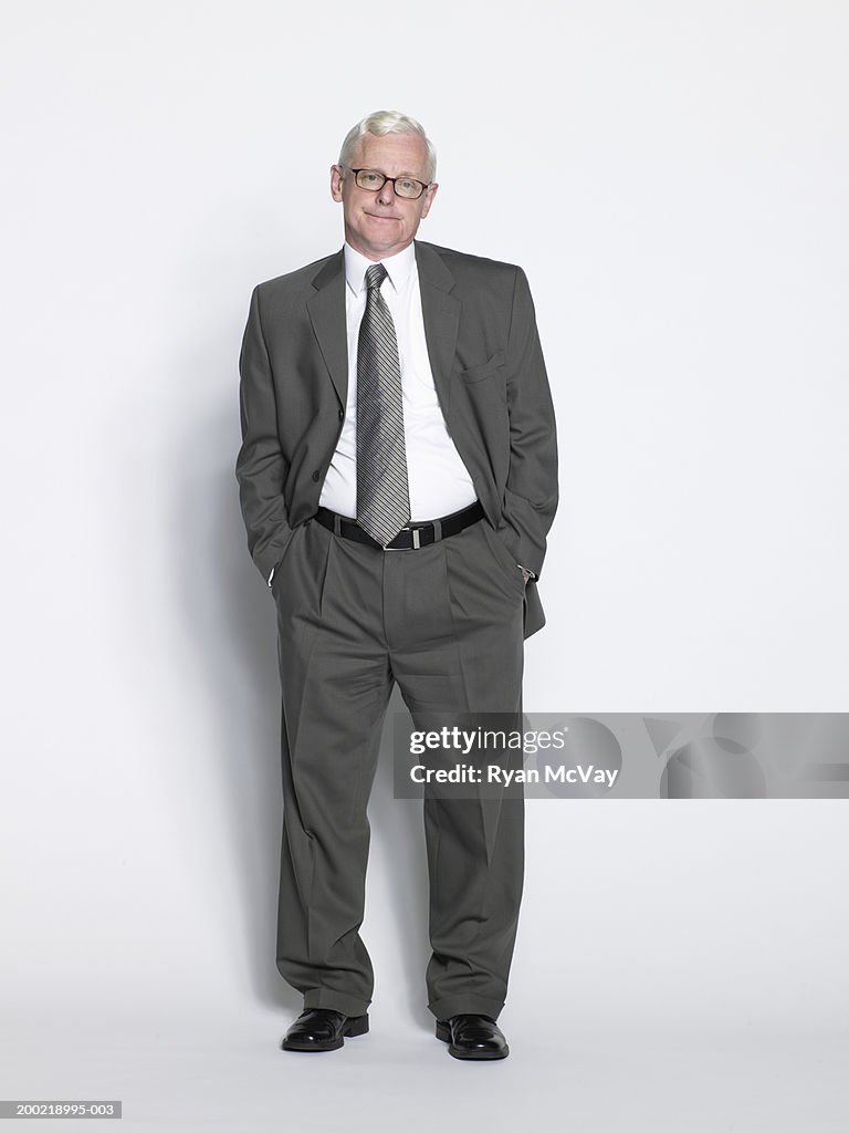 Mature businessman standing with hands in pockets, portrait